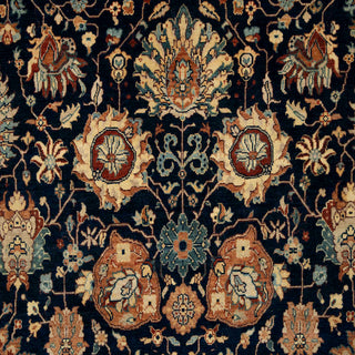 Hand-knotted wool rug featuring intricate floral pattern on deep navy field with caramel and ivory border, 8x10 ft.​