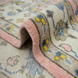 9x12 Turkish Oushak-style hand-knotted rug with pastel floral motif on pink field and ivory border tones