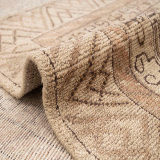Central Asian-style hand-knotted rug with geometric medallion motif in warm camel and beige tones.
