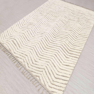 Hand-knotted rug in ivory and beige with chevron zigzag pattern design and tassels.