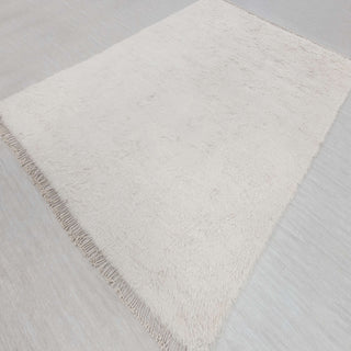 Hand-knotted rug in ivory with solid shag design and subtle fringed edges, large area size