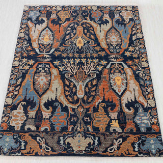 Hand-knotted rug in navy, rust, gold, and blue with bold abstract botanical design, 8x10 size.