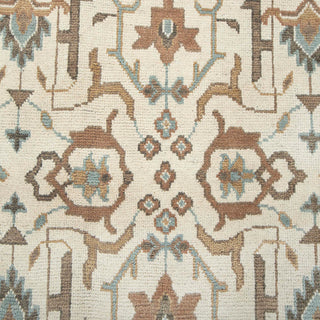 Hand-knotted wool rug featuring allover tribal floral pattern in cream, teal, camel, 9x12 size.

