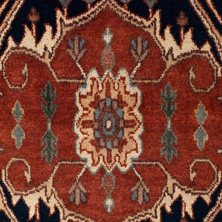 Hand-knotted wool rug featuring central navy medallion and tribal floral motifs in rust, blue, cream, 9x12.