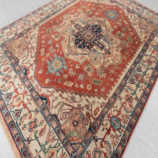 Hand-knotted wool rug featuring central navy medallion, rust field, ivory floral border, 8x10 size.