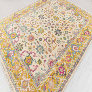 Hand-knotted wool rug featuring dense floral pattern in ivory, gold, teal, fuchsia, 8x10 size.