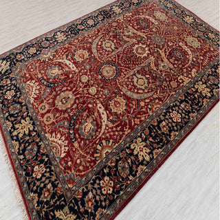 Hand-knotted wool rug featuring detailed floral medallions on rich red field with navy border, classic 6x9 ft
