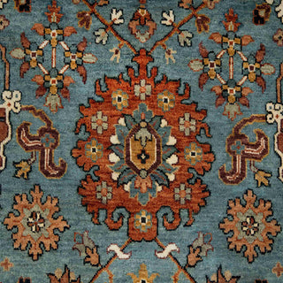 Hand-knotted wool rug featuring traditional geometric floral pattern in blue, rust, ivory, 8x10 size.
