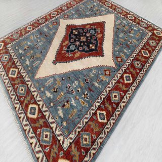 Hand-knotted wool rug featuring tribal diamond medallion and floral motifs in blue, rust, cream, 8x10.