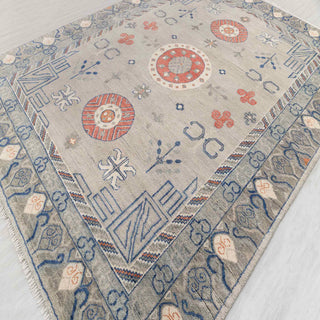 Hand-knotted wool rug featuring tribal medallions and floral motifs in soft grey, blue, terracotta, 9x12.