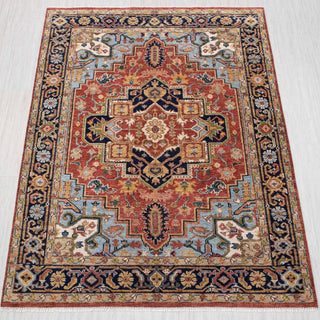 Hand-knotted wool rug in rust, navy, and light blue with geometric medallion design.
