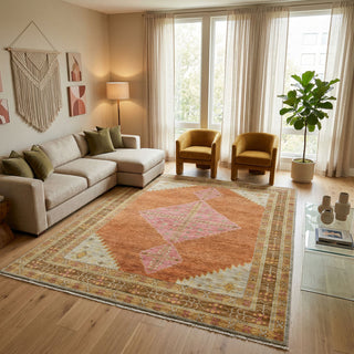 Hand-knotted rug in rust, pink, and gold with large geometric diamond medallion design.
