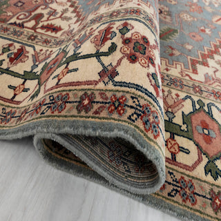 Heriz-style hand-knotted rug with bold geometric medallion and tribal florals in blue, cream, terracotta.