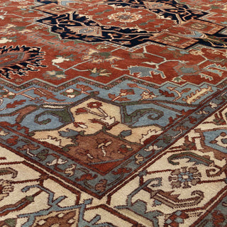 Heriz-style hand-knotted rug with bold geometric medallion motif in terracotta, slate blue, and ivory tones.