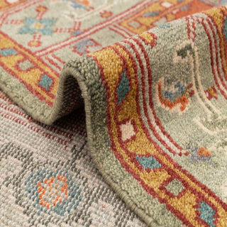 Heriz-style hand-knotted rug with central geometric medallion motif in sage, rust, and soft blue tones.