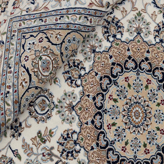 Isfahan-style hand-knotted rug with classic floral medallion motif in ivory, blue, tan tones.