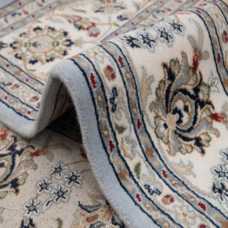 Isfahan-style hand-knotted rug with intricate floral medallion motif in soft blue, ivory, gold tones.