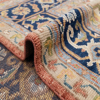 Large hand-knotted area rug with central medallion, navy border, rust field, soft wool pile.