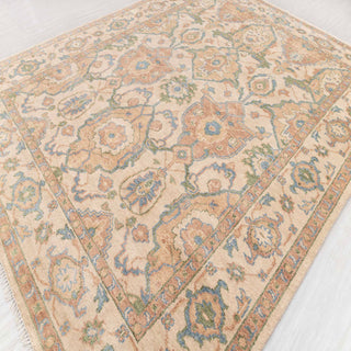 Modern classic hand-knotted rug with distressed floral pattern in neutral ivory, camel, and blue palette.