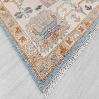 Modern hand-knotted rug with abstract Oushak-inspired floral pattern in blue, beige, tan tones.