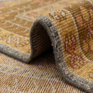 Modern hand-knotted rug with abstract geometric diamond pattern in warm rust, pink, and gold tones.