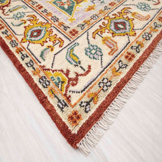 Modern hand-knotted rug with abstract geometric medallion pattern in rust, teal, gold, ivory.