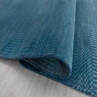 Modern hand-knotted rug with abstract linear pattern in teal, denim, soft blue tones.