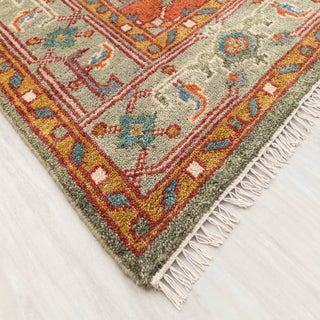 Modern hand-knotted rug with colorful geometric medallion and border design in green, rust, and beige.