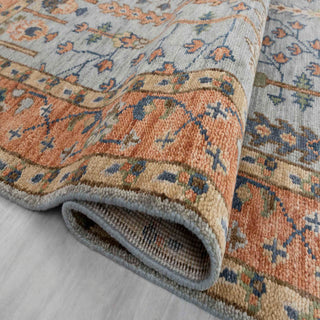 Modern hand-knotted rug with intricate botanical pattern in dusty blue and rust tones, classic area size.