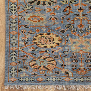 Modern hand-knotted rug with intricate repeating floral pattern in blue, rust, teal and beige accents.