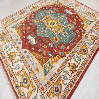 Oushak-style hand-knotted rug with geometric floral motif in rust, teal, gold, ivory tones.