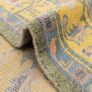 Oushak-style hand-knotted rug with soft floral motifs in green, mustard, and slate blue tones.