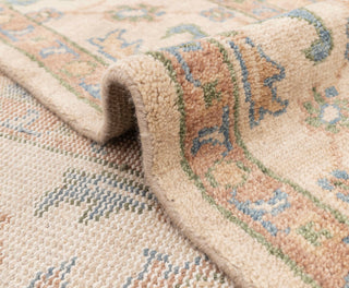 Oushak-style hand-knotted rug with soft repeating palmette motifs in cream, sand, and sky blue tones.