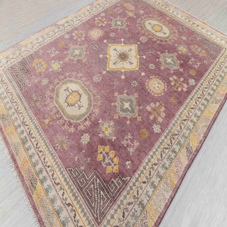 Oushak-style hand-knotted rug with tribal medallion motifs in dusty purple, gold, and soft grey tones.
