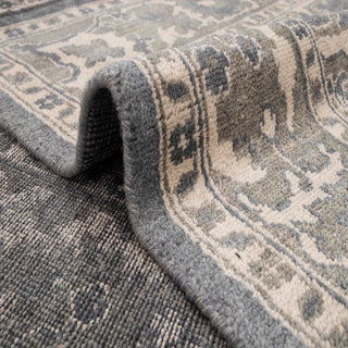 Persian-style hand-knotted rug with intricate floral motif in charcoal, ivory, and soft taupe neutrals.