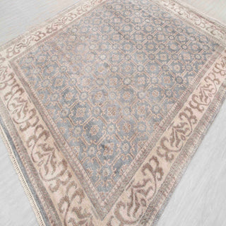 Persian-style hand-knotted rug with tiled medallion motif in soft blue and neutral beige tones.
