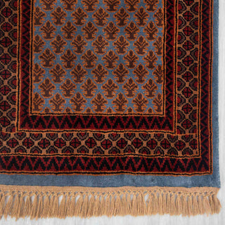Persian Gabbeh-inspired hand-knotted rug with small leaf motifs and geometric border in blue, rust, olive tones