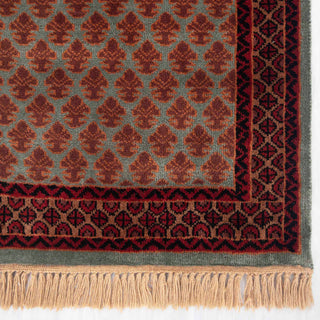 Persian Gabbeh-inspired hand-knotted rug with small leaf motifs and geometric border in rust, green, maroon