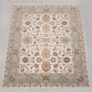 Traditional hand-knotted rug in ivory, blue, and gold with delicate Persian floral design, 8x10 size.