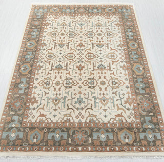 Traditional hand-knotted rug in ivory, brown, blue with ornate geometric floral border design.