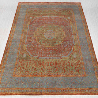 Traditional hand-knotted rug in rust, sage green and soft blue with intricate medallion design.