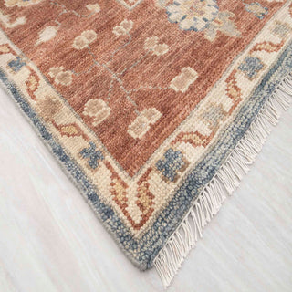 Turkish Oushak-style hand-knotted rug with bold floral motif in denim blue and terracotta tones.