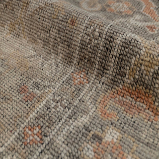 Turkish Oushak-style hand-knotted rug with faded floral motif in neutral gray, rust, taupe tones.
