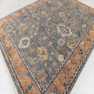Turkish Oushak-style hand-knotted rug with geometric medallion motif in charcoal, rust, and blue.