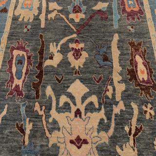 Turkish Oushak-style hand-knotted rug with large abstract floral motif in blue, ivory, orange, plum.
