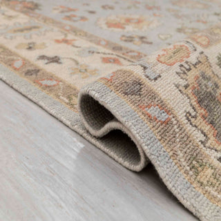 Turkish Oushak-style hand-knotted rug with large floral motif in sky blue, cream, earth tones.