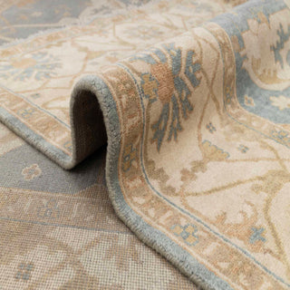 Turkish Oushak-style hand-knotted rug with scrolling floral motif in blue, gold, ivory tones.