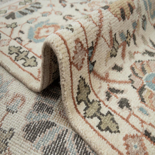 Turkish Oushak-style hand-knotted rug with soft floral motifs in ivory, light blue, and camel tones