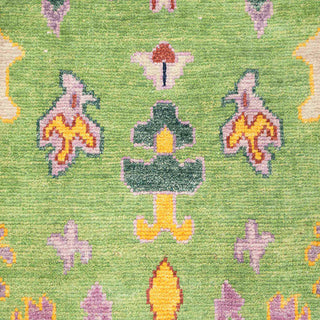 Turkish Oushak-style hand-knotted rug with tribal floral motif in green, yellow, and purple tones.