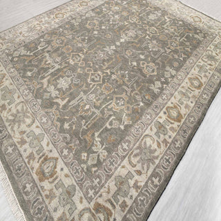 Turkish Oushak-style hand-knotted rug with tribal floral motif in soft gray, ivory, camel tones.